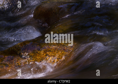 Flusso fresco dei flussi di acqua e cascate sul fiume con rocce scure, struttura granulosa. Foto Stock