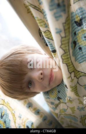 Sette anni di vecchio ragazzo giocando pieghevole con una tenda. Foto Stock