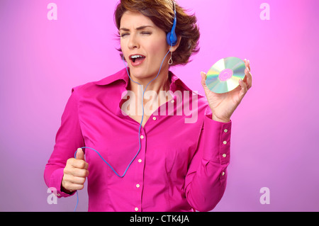Donna attraente, fine 30s - early 40s, ascoltare la musica in cuffia, ballare e cantare insieme con il CD. Foto Stock