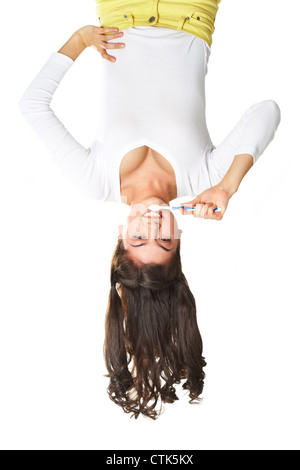 Upside-down colpo verticale di una sorridente ragazza teen facendo mattina procedure igieniche Foto Stock