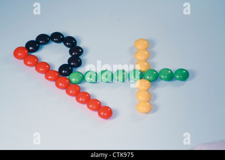 Multi-caramelle colorate disposte in forma di Rx Simbolo su sfondo bianco Foto Stock