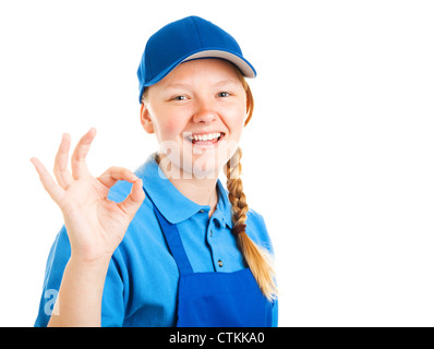 Bella bionda ragazza adolescente in un uniforme di lavoro, dando il segno va bene. Isolato su bianco. Foto Stock