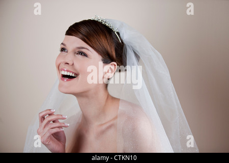 Una giovane sposa che indossa un diadema e velo, ridendo Foto Stock