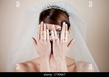 Una giovane sposa che copre il volto con le mani Foto Stock