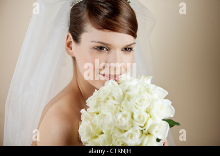 Una giovane sposa tenendo un bouquet di rose bianche Foto Stock