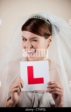 Una giovane sposa in possesso di un permesso di studente piastra, winking Foto Stock