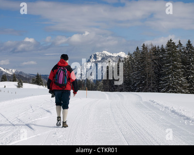 Panorama di montagne coperte di neve e foresta sul confine tra Germania e Austria in Baviera con la mezza età a piedi maschio Foto Stock