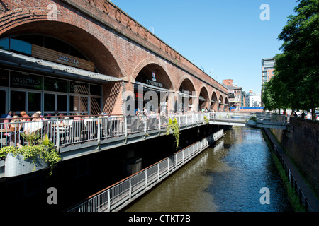 Le persone godono di socializzare con un drink al sole estivo a Deansgate Locks in Manchester. Foto Stock