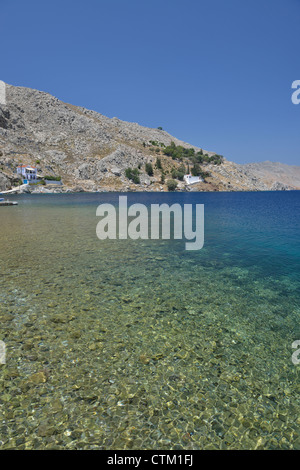 Le acque cristalline a Nimborios con la basilica paleocristiana fino in background; Symi, Dodecaneso. La Grecia. Foto Stock