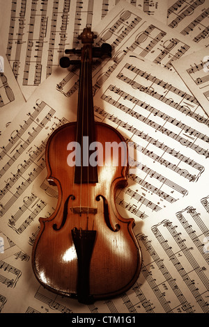 Il legno vecchio violino giacente su note musicali closeup Foto Stock