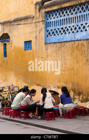 I clienti seduti su bassi sgabelli in plastica a mangiare un cibo di strada a base di noodle stallo in Hoi An, Viet Nam Foto Stock