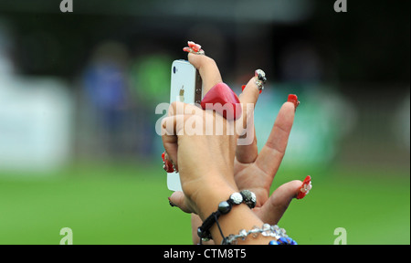 Giovane donna con allestita unghia design e cuore rosso forma anello sul dito prendendo foto sul telefono cellulare Foto Stock