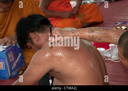 Maglietta rossa guardie ricevere 'Sak Yan' durante l'occupazione di Bangkok in primavera 2010 Foto Stock