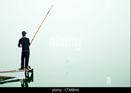 Un pescatore solitario in corrispondenza di West Lake in Hanoi, Vietnam Foto Stock