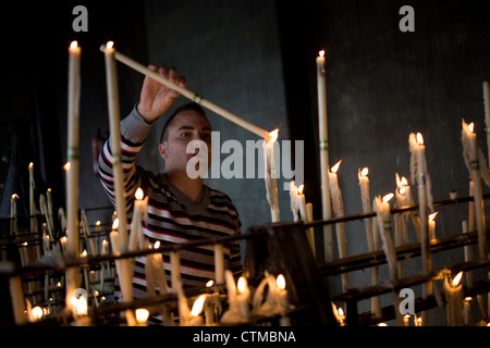 Un uomo accende una candela nella camera votiva del Santuario di Nostra Signora del Rocio a El Rocio village, Huelva, Andalusia, Spagna Foto Stock