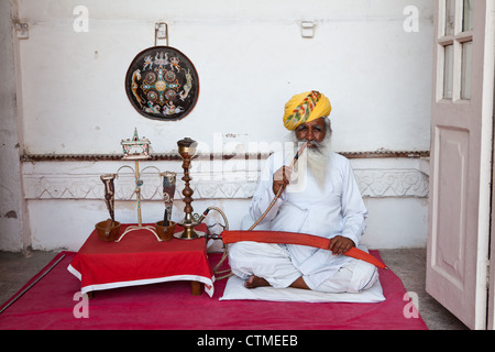 Anziani uomo indiano in turbante il fumo da un narghilè tubazione in Forte Mehrangarh, Jodhpur Foto Stock