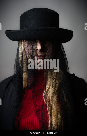 Una bionda e giovane ragazza dai capelli donna che indossa un cappello con nero lutto vittoriano laccio che copre il volto Foto Stock