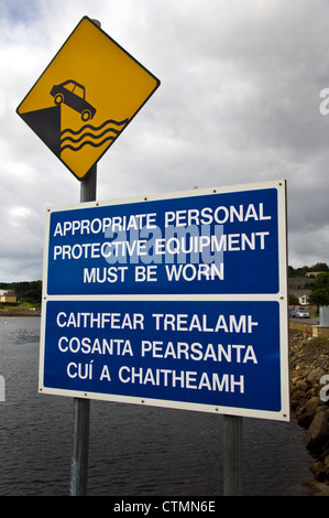 Cartelli di avvertimento in inglese e in gaelico irlandese lingua sul lato del porto quay Foto Stock