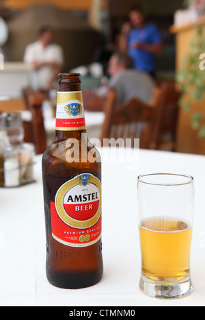 Una bottiglia di vetro e di Amstel birra lager in una taverna greca in RETHIMNO, CRETA Foto Stock