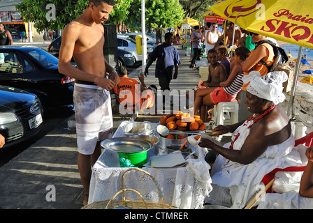 Salvador, Brasile, un uomo locale acquisto Acaraje sapere come locale soul food in strada. Foto Stock