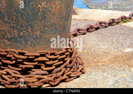 Arrugginimento catena attorno un ormeggio bollard sulla parete del porto a Porlock, Somerset. Foto Stock