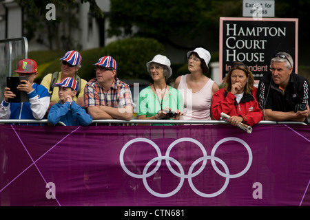 Gli spettatori locali al di sotto della strada di accesso segno attendono il passaggio del peloton il primo giorno di gara del London 2012 Olympic 250km mens' la gara su strada. A partire da Londra centrale e passando la capitale più famosi luoghi di interesse prima di uscire in Inghilterra rurale all'estenuante Box Hill nella contea del Surrey. Sud-ovest locali londinesi rivestito il percorso sperando per preferito britannico Mark Cavendish per vincere Team GB prima medaglia ma che sono poi stati delusi quando il Kazakistan è Alexandre Vinokourov alla fine ha vinto l'oro. Foto Stock