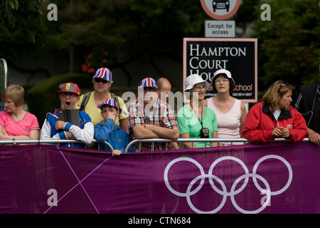 Gli spettatori locali al di sotto della strada di accesso segno attendono il passaggio del peloton il primo giorno di gara del London 2012 Olympic 250km mens' la gara su strada. A partire da Londra centrale e passando la capitale più famosi luoghi di interesse prima di uscire in Inghilterra rurale all'estenuante Box Hill nella contea del Surrey. Sud-ovest locali londinesi rivestito il percorso sperando per preferito britannico Mark Cavendish per vincere Team GB prima medaglia ma che sono poi stati delusi quando il Kazakistan è Alexandre Vinokourov alla fine ha vinto l'oro. Foto Stock