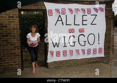 Spettatori godetevi un piacevole dessert di fragole al fianco dei loro banner di fortuna al team di GB di ciclismo su strada hero Bradley Wiggins, un recente vincitore del legedary Tour de France. Questa è la prima giornata di gara del London 2012 Olympic 250km mens' la gara su strada. A partire da Londra centrale e passando la capitale più famosi luoghi di interesse prima di uscire in Inghilterra rurale all'estenuante Box Hill nella contea del Surrey. Foto Stock