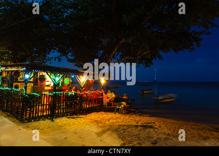 I turisti potranno gustare rinfreschi nel bar sulla spiaggia illuminato di sera a Little Corn Island, Nicaragua. Foto Stock