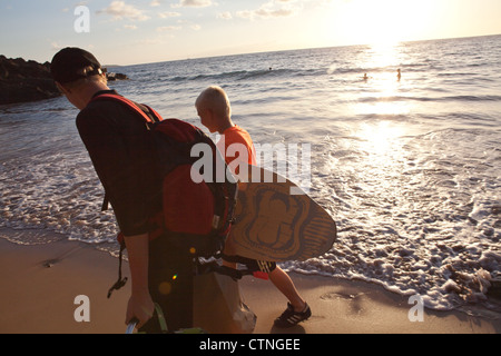 Ragazzi che trasportano skimboards, Maui, Hawaii Foto Stock