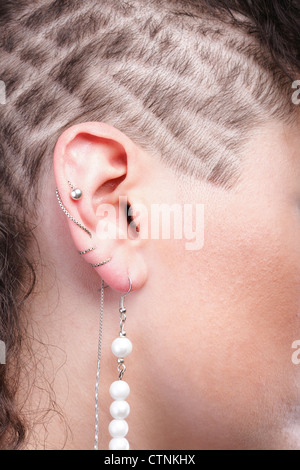 Ragazza - ear piercing super donna capelli scuri marrone naturale dai capelli sfondo nero Foto Stock