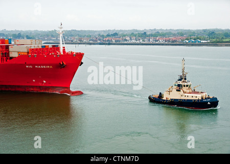 Rimorchiatore manouevres contenitore grande nave in Southampton acqua, Inghilterra Foto Stock