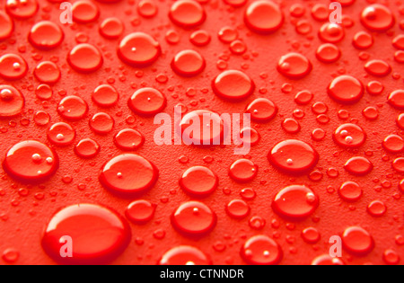 Lucido di gocce di acqua spruzzata sulla trama della superficie rossa. Foto Stock