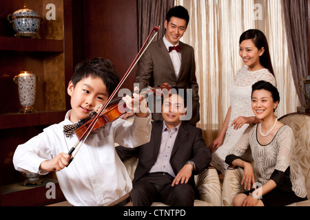 Little Boy suona il violino nella parte anteriore dei membri della famiglia Foto Stock