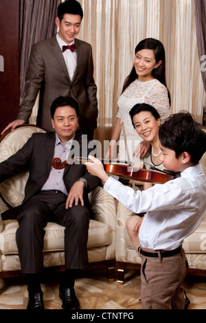 Little Boy suona il violino nella parte anteriore dei membri della famiglia Foto Stock