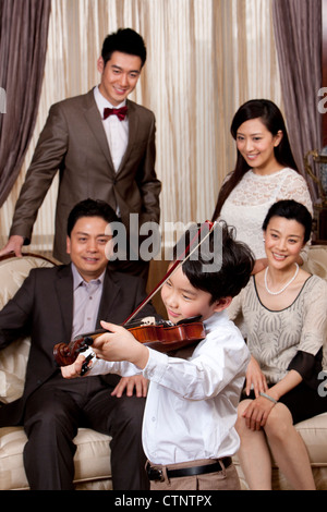 Little Boy suona il violino nella parte anteriore dei membri della famiglia Foto Stock