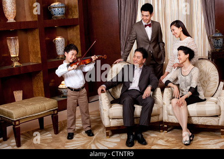 Little Boy suona il violino nella parte anteriore dei membri della famiglia Foto Stock