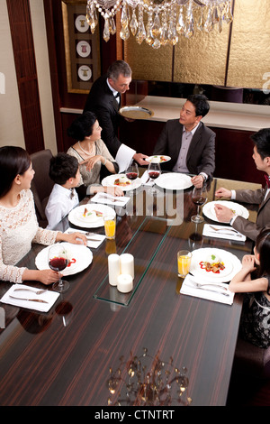 Famiglia avente la cena in una lussuosa sala da pranzo Foto Stock