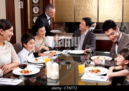 Famiglia avente la cena in una lussuosa sala da pranzo Foto Stock