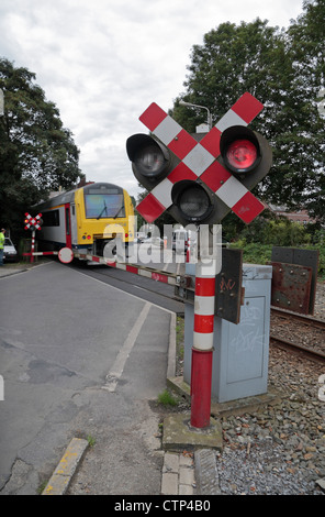 Luci rosse lampeggianti come un treno che passa su un passaggio a livello su una strada vicino a Mons in Belgio, Europa. Foto Stock