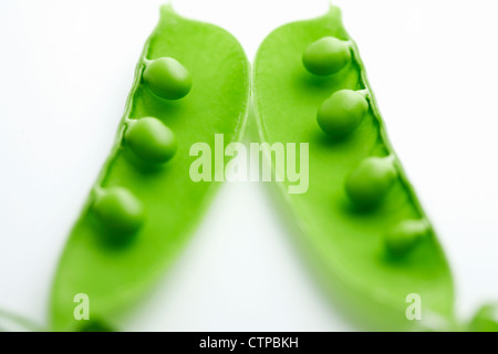 Un close-up di un pea pod split aprire rivelando i piselli su sfondo bianco Foto Stock