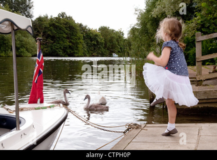 Giovani 5 anno vecchia ragazza alimentazione dei cigni, fiume il Tamigi a Wallingford Oxfordshire UK Foto Stock