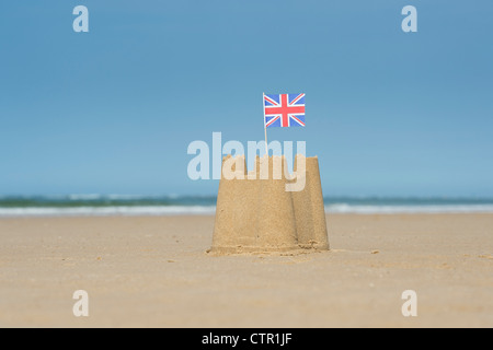 Union Jack flag in un castello di sabbia sulla spiaggia. Pozzetti accanto al mare. Norfolk, Inghilterra Foto Stock