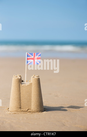 Union Jack flag in un castello di sabbia sulla spiaggia. Pozzetti accanto al mare. Norfolk, Inghilterra Foto Stock