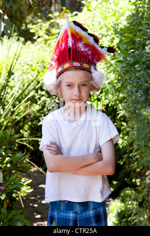 Un ragazzo biondo indossando un giocattolo copricapo indiano. Foto Stock