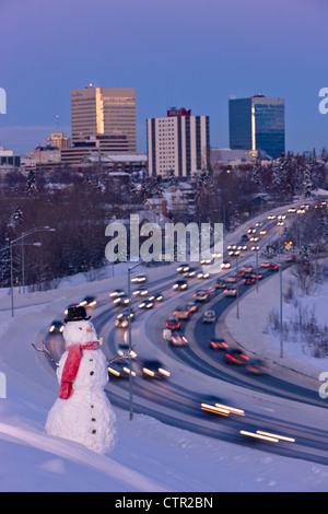 Vista del traffico e il centro cittadino di Anchorage con un pupazzo di neve in primo piano, centromeridionale Alaska, l'inverno. Altered digitalmente. Foto Stock