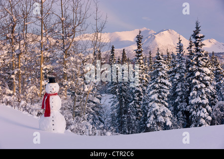 Vista panoramica Chugach Mountains pupazzo di neve indossando sciarpa top hat in primo piano centromeridionale Anchorage in Alaska inverno Foto Stock