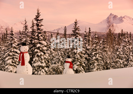 Vista panoramica Chugach Mountains adulto bambino pupazzi di neve indossando sciarpa top hat in primo piano centromeridionale Anchorage in Alaska inverno Foto Stock