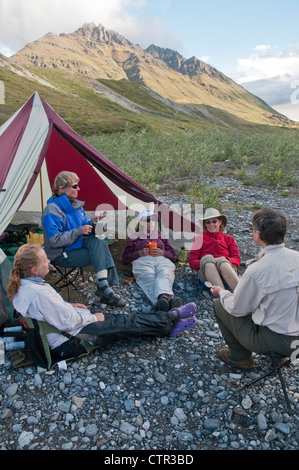 Femmina matura escursionisti relax campeggio lungo il Marsh forcella Canning nel fiume Brooks Range Arctic National Wildlife Refuge Alaska estate Foto Stock