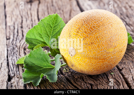 Il melone con le foglie sul vecchio tavolo in legno. Foto Stock